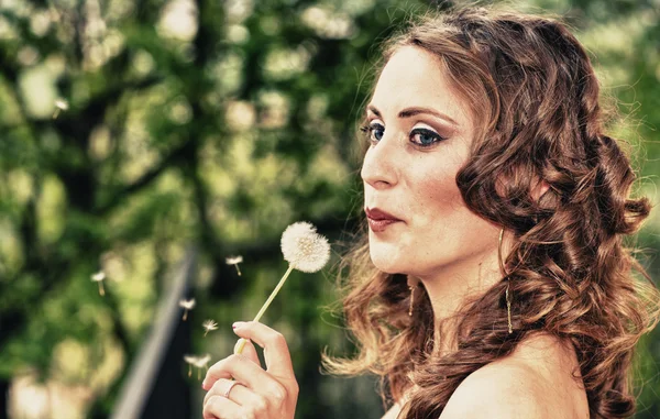 美しい若い女性はタンポポの花を吹いて — ストック写真