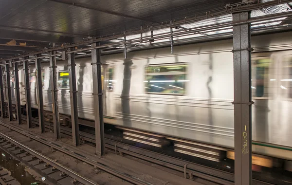 Trem de prata acelerando em um interior de estação de metrô — Fotografia de Stock