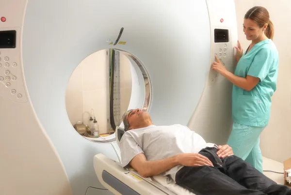 Young female doctor examining man in 40s with CT scanner. Comput — Stock Photo, Image