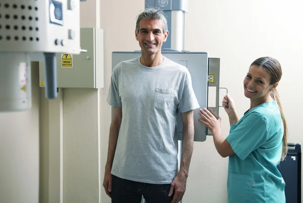 Šťastné ženy doktor připravena k obrazovce mužský pacient na xray stroj — Stock fotografie