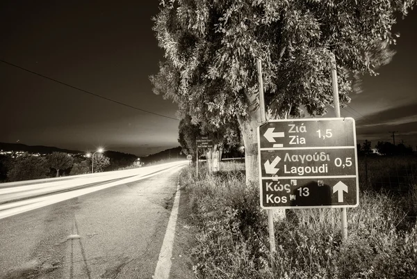 Road directions in Kos with car light trails — Stock Photo, Image