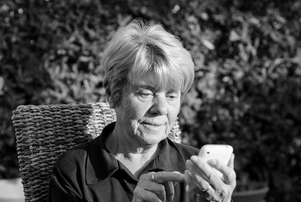 Retired Woman relaxing outdoor with her Smartphone — Stock Photo, Image