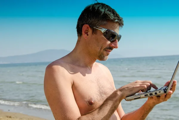 Mann entspannt sich am Strand mit seinem Notizbuch — Stockfoto