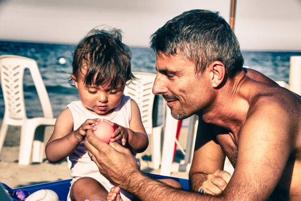 Baby og hendes far leger på havet på Sicilien - Stock-foto