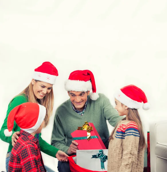 Gelukkige familie dragen rode hoeden kijken naar Kerstmis geschenken, isolat — Stockfoto