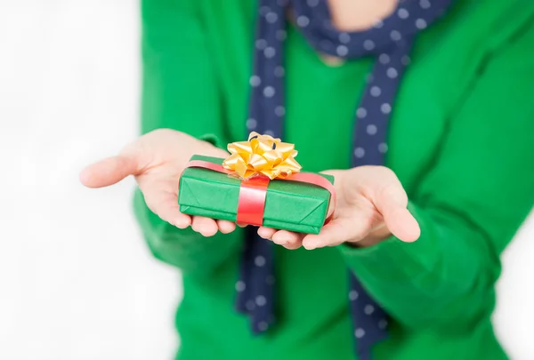 Bella ragazza mostrando piccolo regalo sulle sue mani, isolato su bianco — Foto Stock