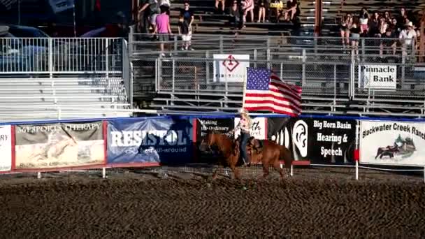 CODY, WY - Temmuz 2019: Kız ata biniyor ve Rodeo Park 'ta Amerikan bayrağı taşıyor — Stok video