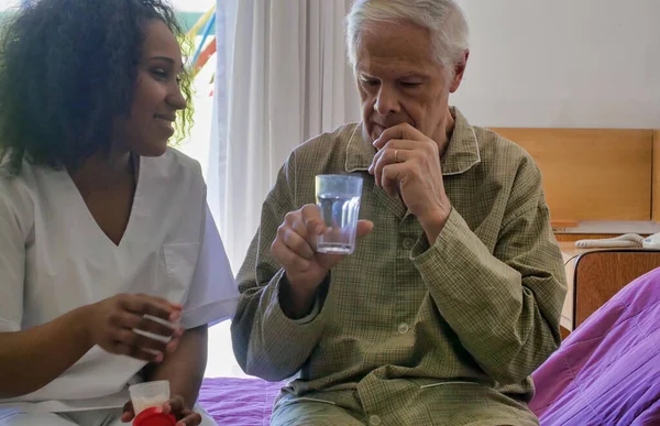 Médica Africana Dando Pílula Médica Para Idosos Aposentado Homem Cama — Fotografia de Stock