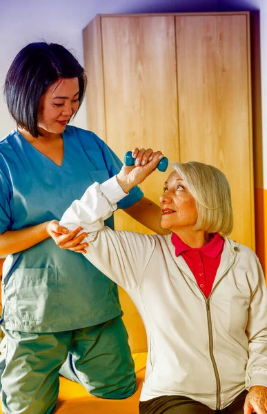 在护士的帮助下在医院体育馆做运动的老年妇女 — 图库照片