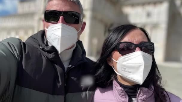 Casal caminhando perto de um marco da cidade usando máscara bucal na pandemia vívida — Vídeo de Stock