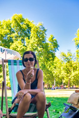 Yaz mevsiminde parkta dondurma yiyen bir kadın. Turizm konsepti