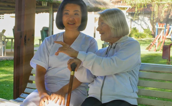 아시아 의사는 보행기를 여자와 이야기를 나누었는데 벤치에 있었다 — 스톡 사진