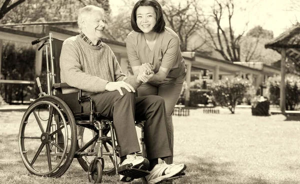 Asian Nurse Happy Caucasian Elder Patient Wheelchair Outdoor View — Stock Photo, Image