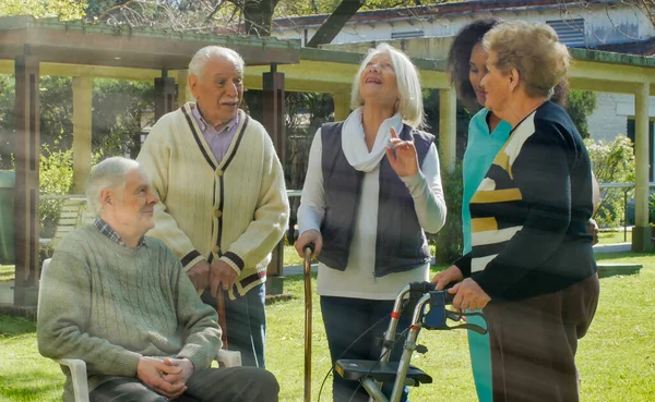 非洲护士在康复医院花园与两位退休的老年夫妇交谈 康复和退休概念 — 图库照片