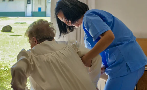 Молодая Азиатка Врач Помогает Пожилой Пенсионерке Ложиться Больничную Койку — стоковое фото