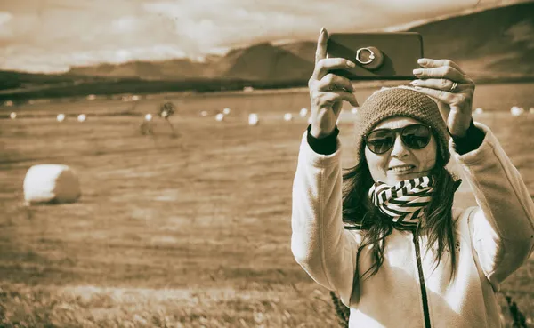 幸せな女性は携帯電話で自撮り 背景に干し草の山の俵 — ストック写真