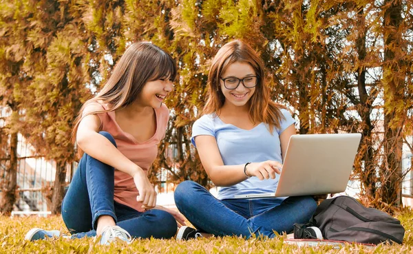 亚洲少女和她的高加索朋友一起躺在草地上使用笔记本电脑 幸福与光明的概念 — 图库照片