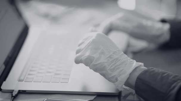 Uomo che indossa guanti usando il computer portatile in tempo pandemico. Vista in bianco e nero — Video Stock