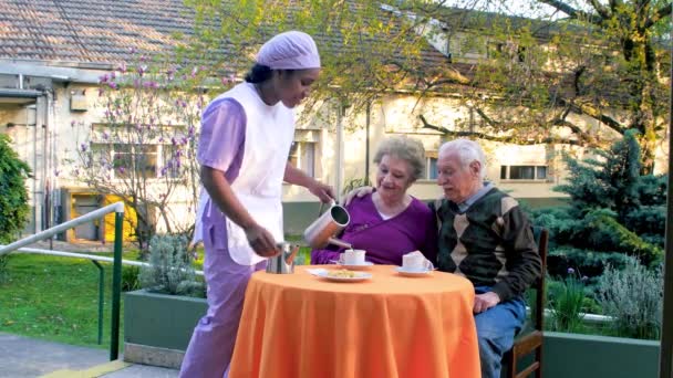 Casal de idosos tomando café da manhã ao ar livre servido por anfitrião feminino. Idosos activos — Vídeo de Stock