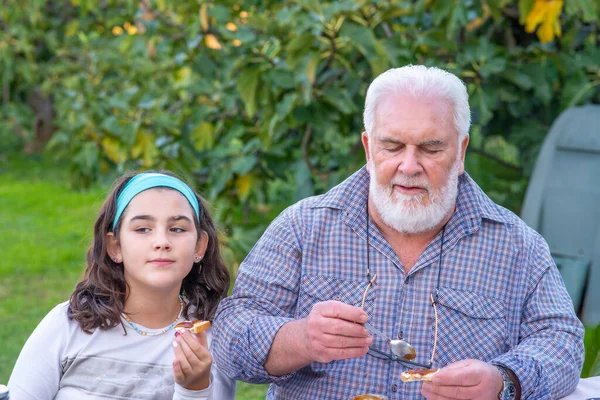 老年人和孙子孙女们一起在户外吃着一片面包上的无花果果酱 — 图库照片