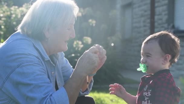 Abuela y nieto jugando juntos y relajándose al aire libre en una hermosa tarde soleada en el patio trasero del hogar — Vídeos de Stock