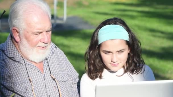 Пожилой человек объясняет, как использовать ноутбук своей внучке — стоковое видео