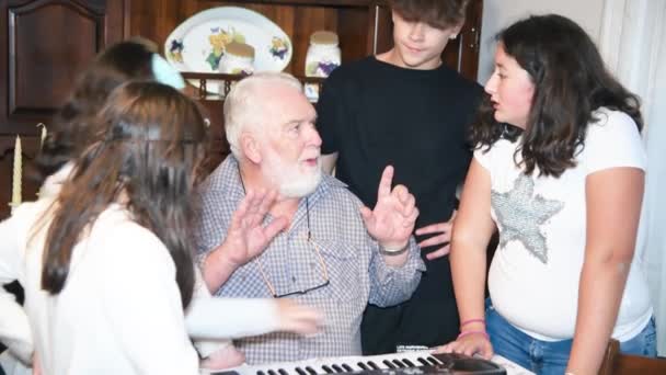 Дідусь пояснює, як використовувати електричне піаніно своїм онукам вдома — стокове відео