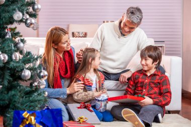 Mutlu gülümseyen beyaz aile Noel hediyelerini açıyor.