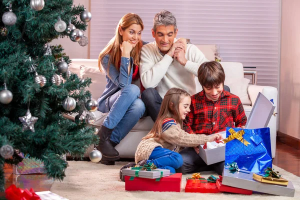 クリスマスのために家で幸せな笑顔の白人家族クリスマスプレゼントをアンラッピング — ストック写真