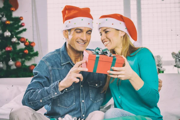 幸せな笑顔若いカップル身に着けているクリスマスの帽子オープンクリスマスギフトで家 — ストック写真