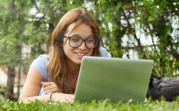 白人少女躺在草地上用笔记本电脑 幸福与光明的概念 — 图库照片