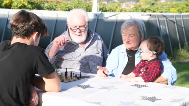 Бабусі і дідусі грають разом і відпочивають на відкритому повітрі в красивий сонячний день на домашньому дворі — стокове відео