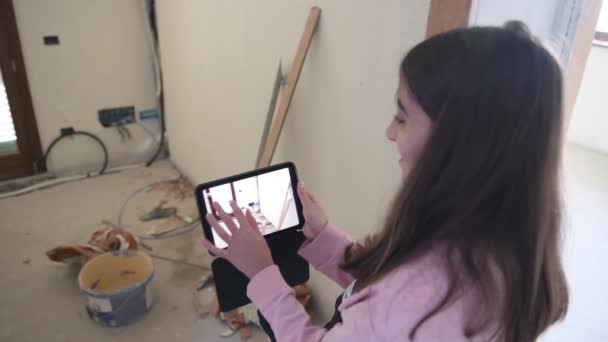 Молода дівчина розміщує предмети меблів у доповненій реальності зі своїм планшетом. Переїзд в новий будинок — стокове відео