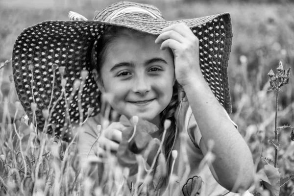 若いです女の子タッチA赤ケシで真ん中の美しいですケシ草原で春の季節 — ストック写真