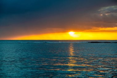 Okyanusun üstünde inanılmaz bir gün batımı. Sarı, mavi ve turuncu renkler