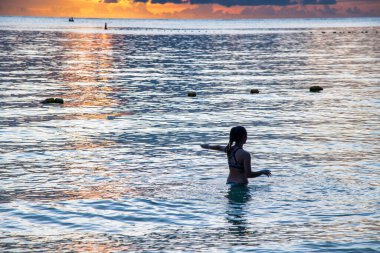 Gün batımında suda oynayan genç bir kızın gölgesi