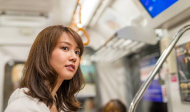 Asian girl standing inside city subway train.