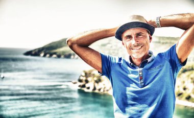 Hasır şapkalı adam denizde dinleniyor, arkada okyanus var..