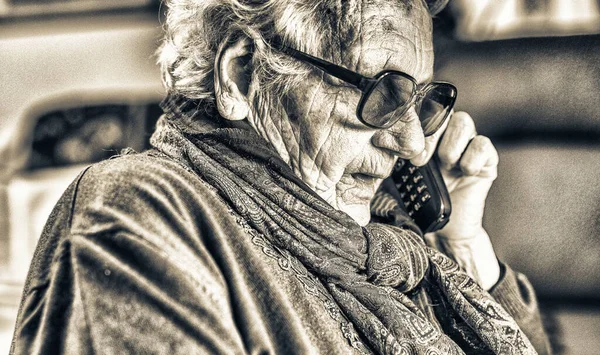 家中戴眼镜看手机的老年妇女 — 图库照片