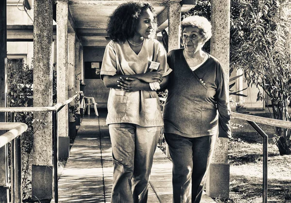 Afrikalı Kadın Doktor Hastane Bahçesinde Yaşlı Emekli Bir Kadınla Konuşuyor — Stok fotoğraf