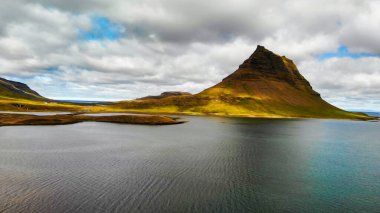 Arkasında göl ve okyanus olan ünlü İzlanda dağı Kirkjufell. Kirkjufell Dağı, yaz mevsiminde Snaefellsnes Yarımadası 'nda İHA bakış açısıyla.