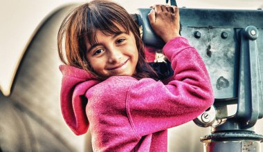 Mutlu gülümseyen genç kız bir teleskop tutarak şehir ziyaret.