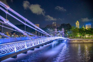 Singapur nehri boyunca gece aydınlatılmış bir köprü.