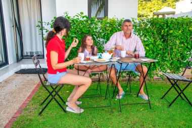 Family relaxing making breakfast outdoor in the garden