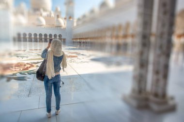 Muslim girl visiting beautiful Mosque on a sunny day, back view