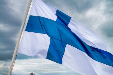 Finlandiya ulusal bayrağı bulutlu bir havada rüzgarda dalgalanıyor