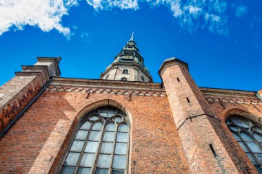 Orta Çağ Aziz Peter Kilisesi 'nin ve eski Riga, Letonya' daki dekoratif pencerelerinin tepesinde altın horozlu bir kule.