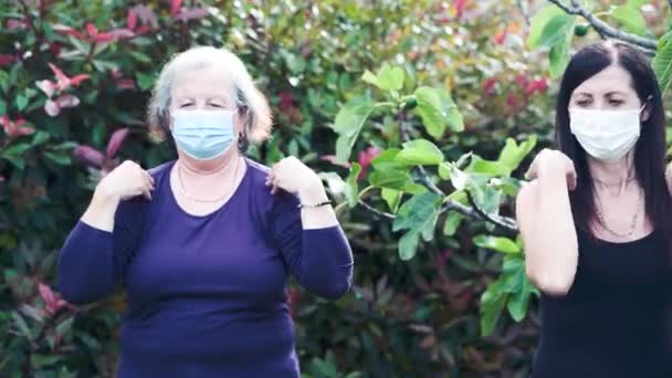 Четыре женщины тренируются в саду в масках. Тренировки на открытом воздухе во время вспышки коронавируса. Здоровые женщины — стоковое видео