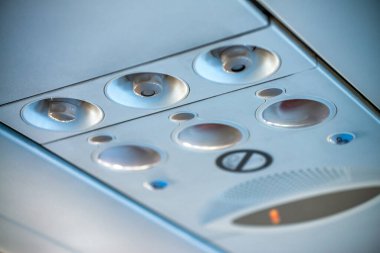 Uçaktaki koltukların üstündeki tipik yolcu kontrol paneli. Hava, ışık ve emniyet kemeri için tabela kontrolü ve sigara içmek yasak.