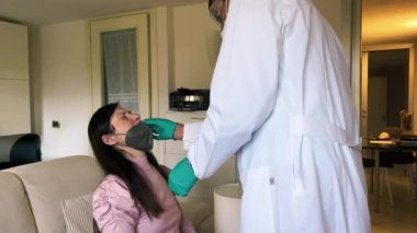 Evde kapalı kapılar ardında önleme. Doktor, kadın hastayı burun temizleme testi ile test ediyor. .